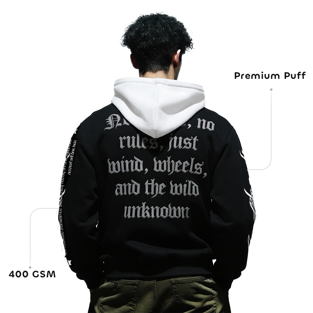 Person wearing a black hoodie with white text on the back, standing against a white background.
